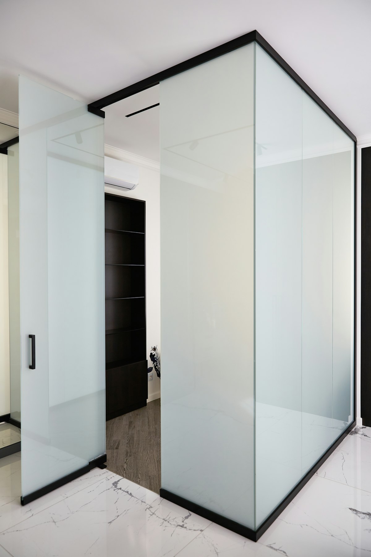 Black-framed glass room divider separating two zones in a broken-plan living space