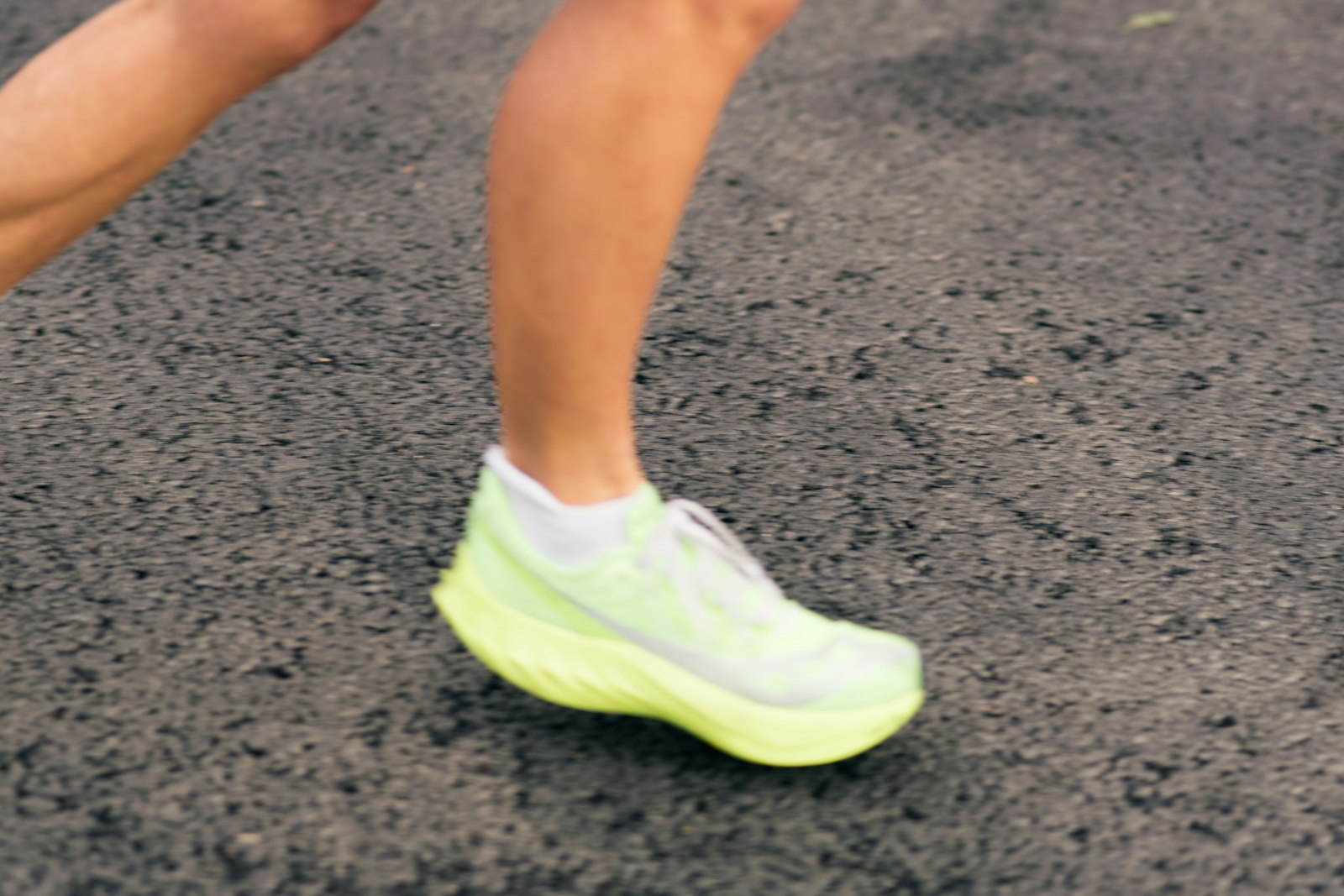 Close-up of a runner's foot in a bright green racing shoe on tarmac