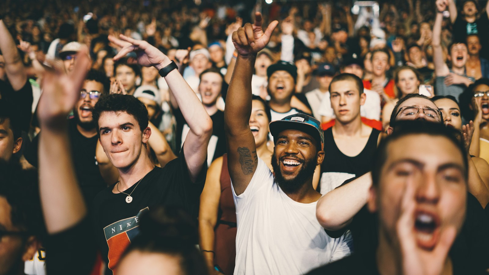 Excited crowd with raised arms at an arena concert