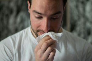 A man blowing his nose into a tissue - the start of Britain's cold and flu season and the search for cold and flu remedies that actually work