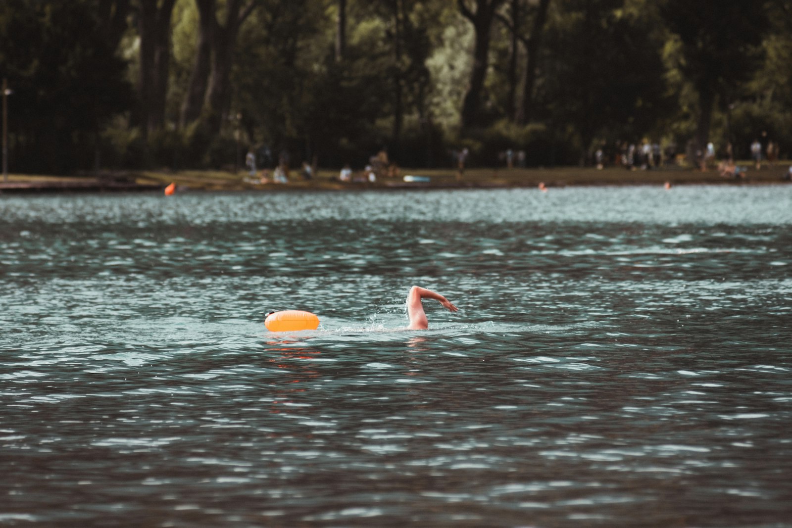 Swimmer in a lake with an orange tow float for visibility