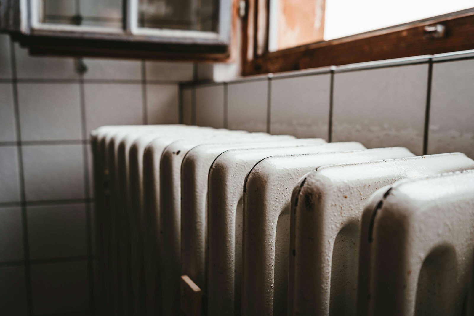 Cast iron column radiator in raw metal finish against a painted wall
