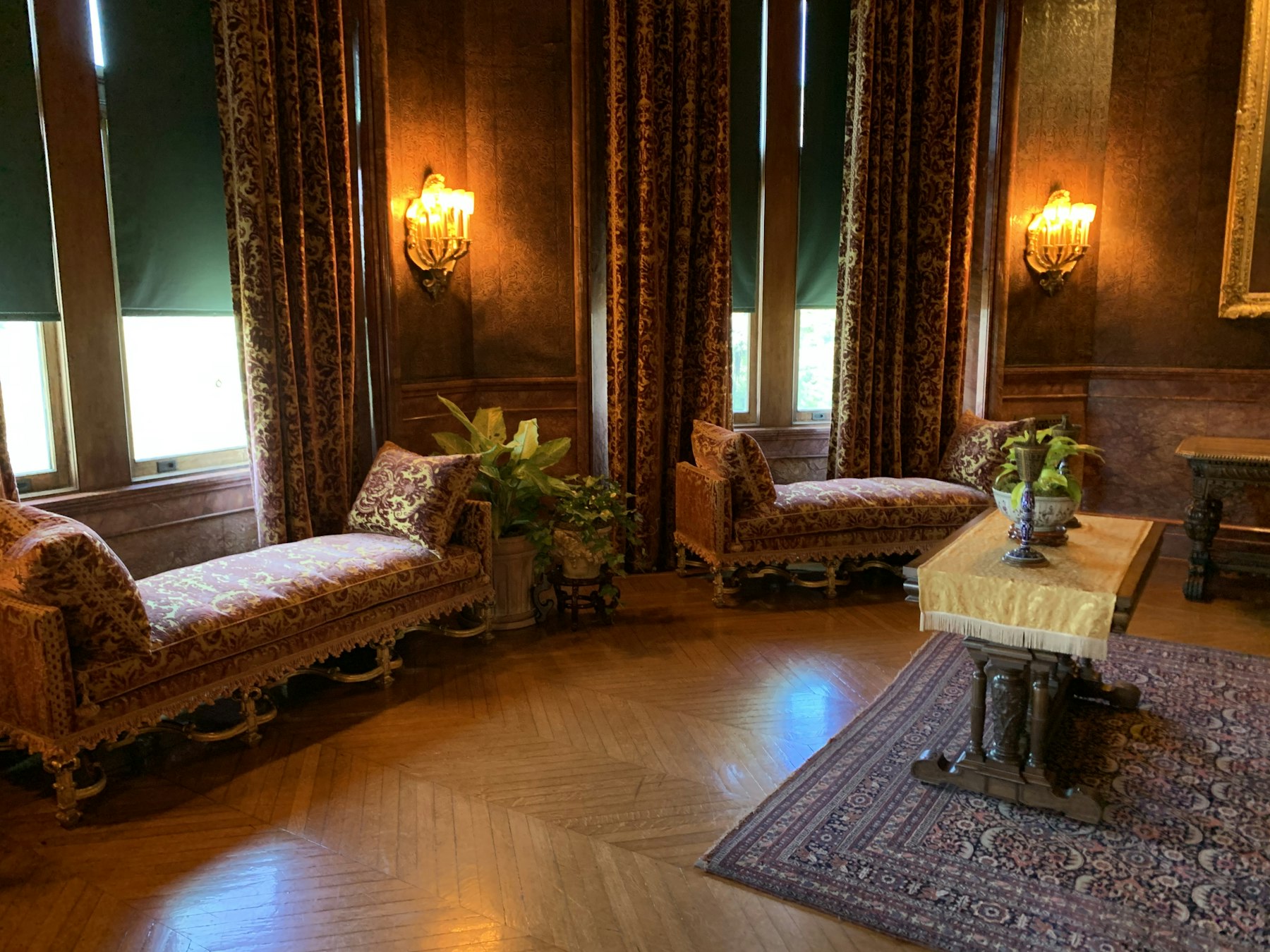 Grand sitting room with heavy brown curtains and pelmets at tall windows, showing the traditional look driving curtain trends 2026