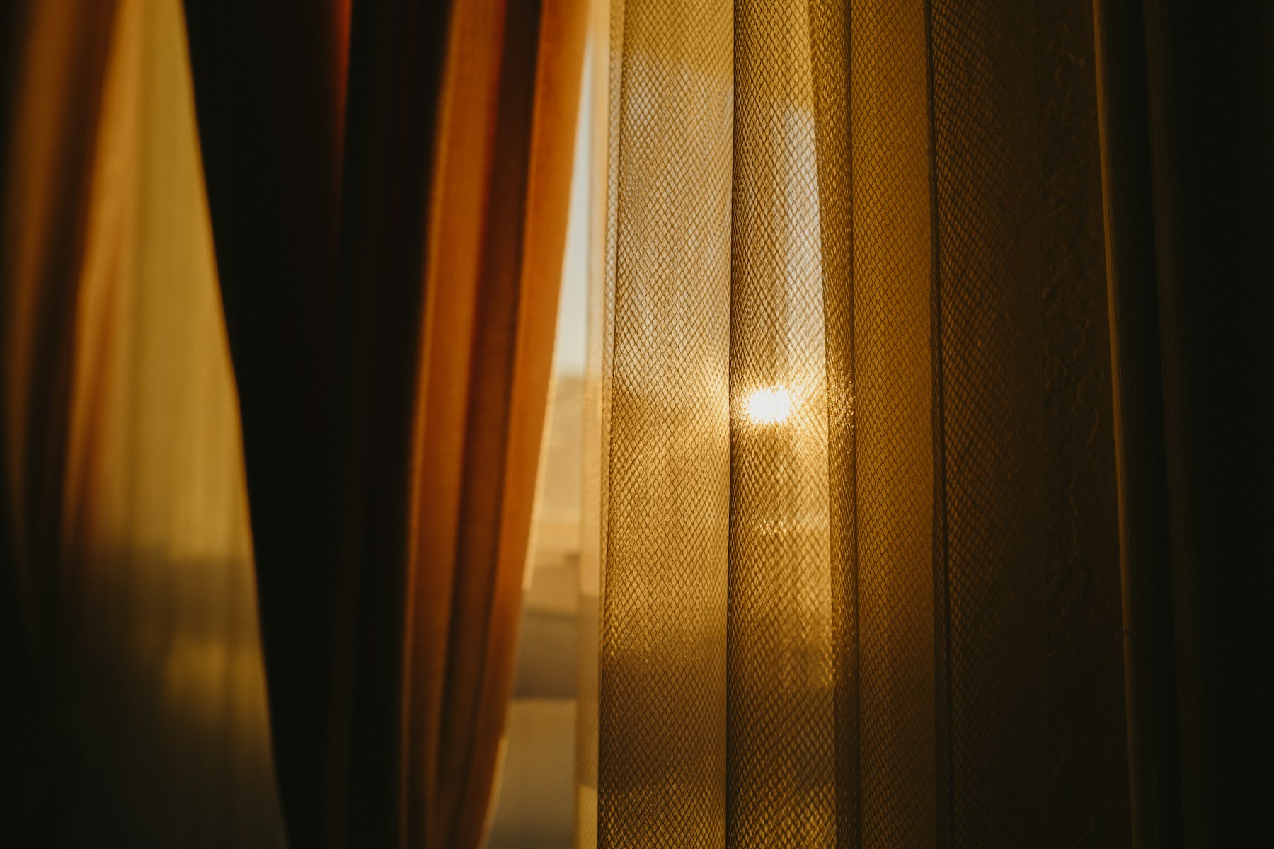 Warm autumn light through heavy brown lined curtains at a window