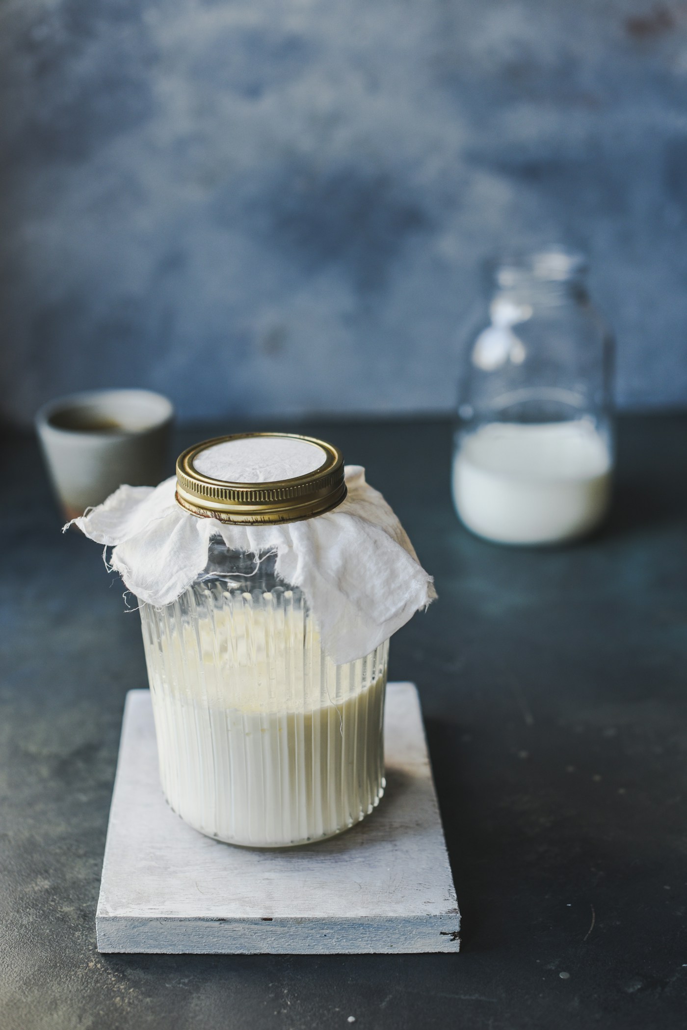 Glass jar of home-made kefir covered with a cloth - live yoghurt and kefir give a mixed dose of cultures for about £1.50