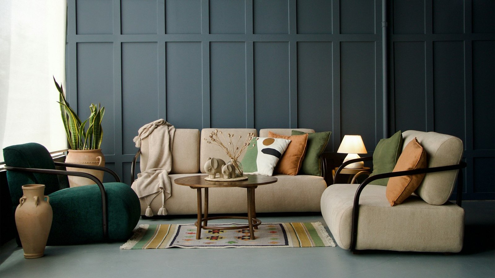 Living room with dark grey-green panelled walls, cream sofa and sage cushions
