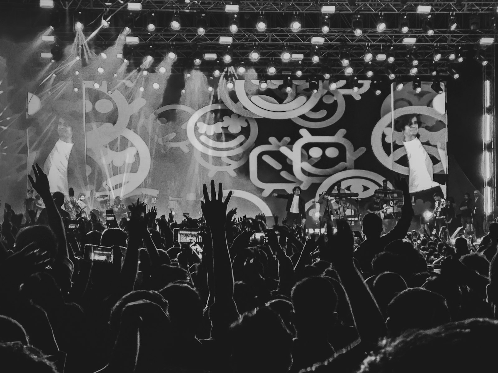 Concert crowd with hands raised under stage lights at night