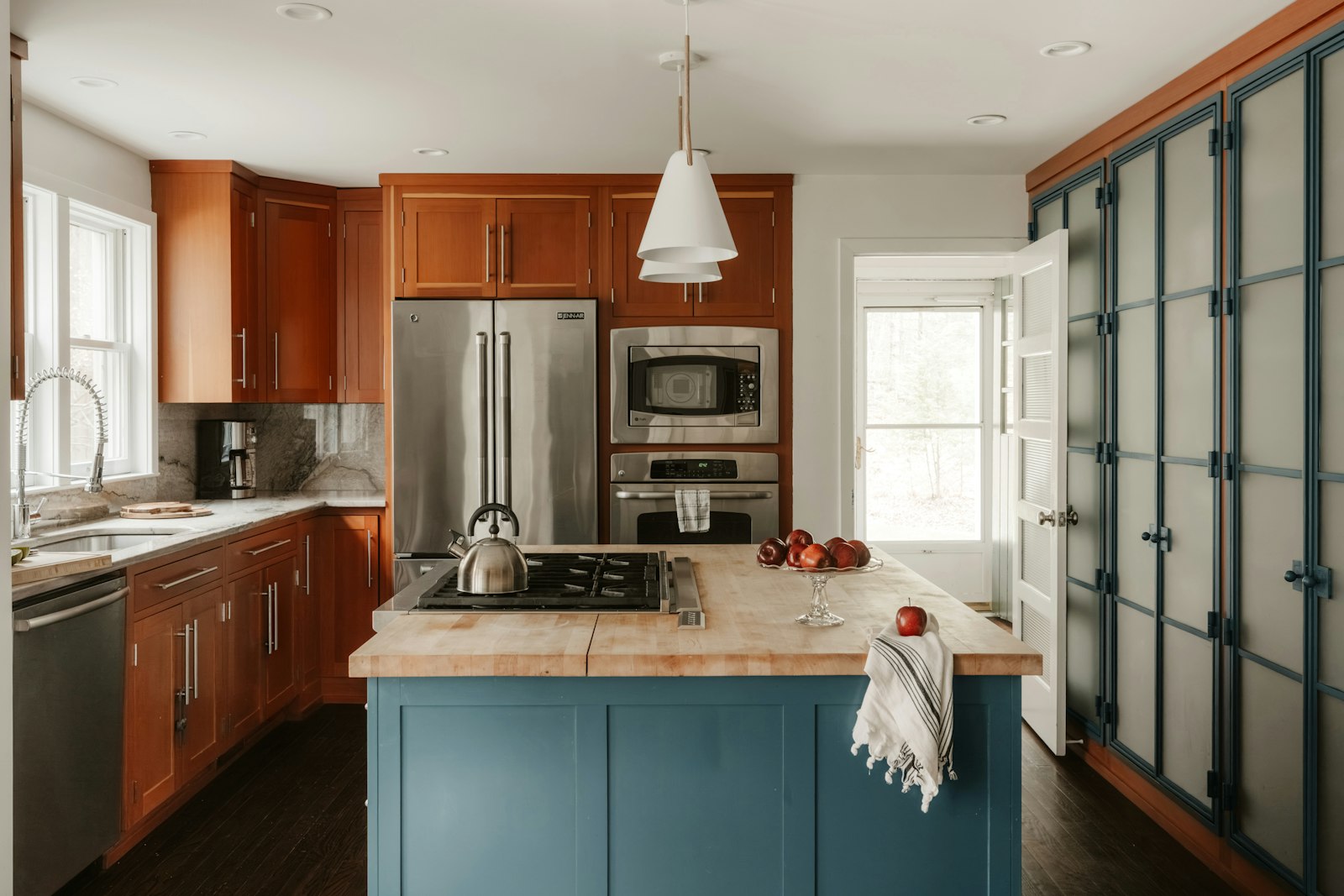 Kitchen trends 2026 - a blue kitchen island set against warm wood cabinetry