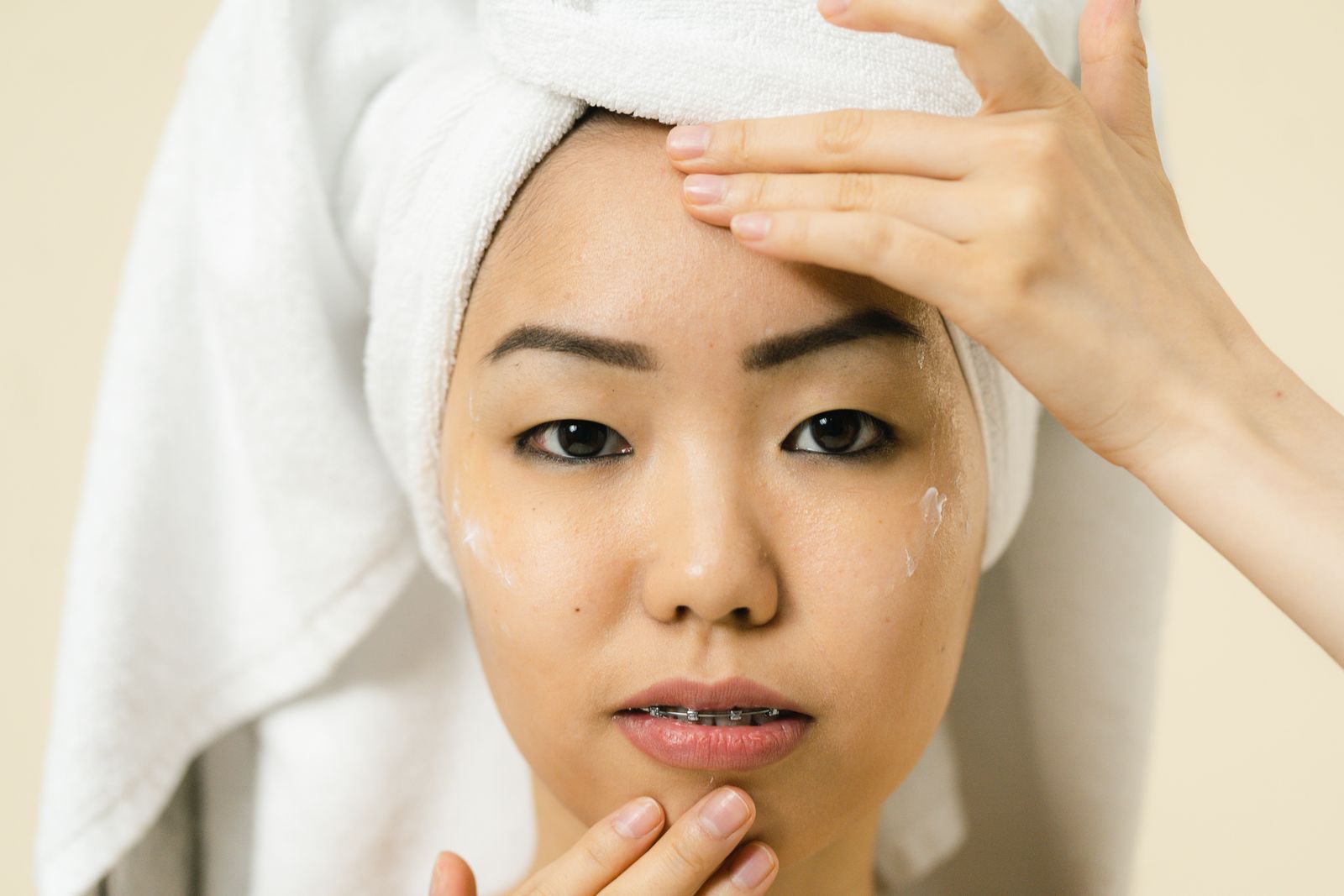 Woman applying retinoid cream and SPF as part of an evening skincare routine