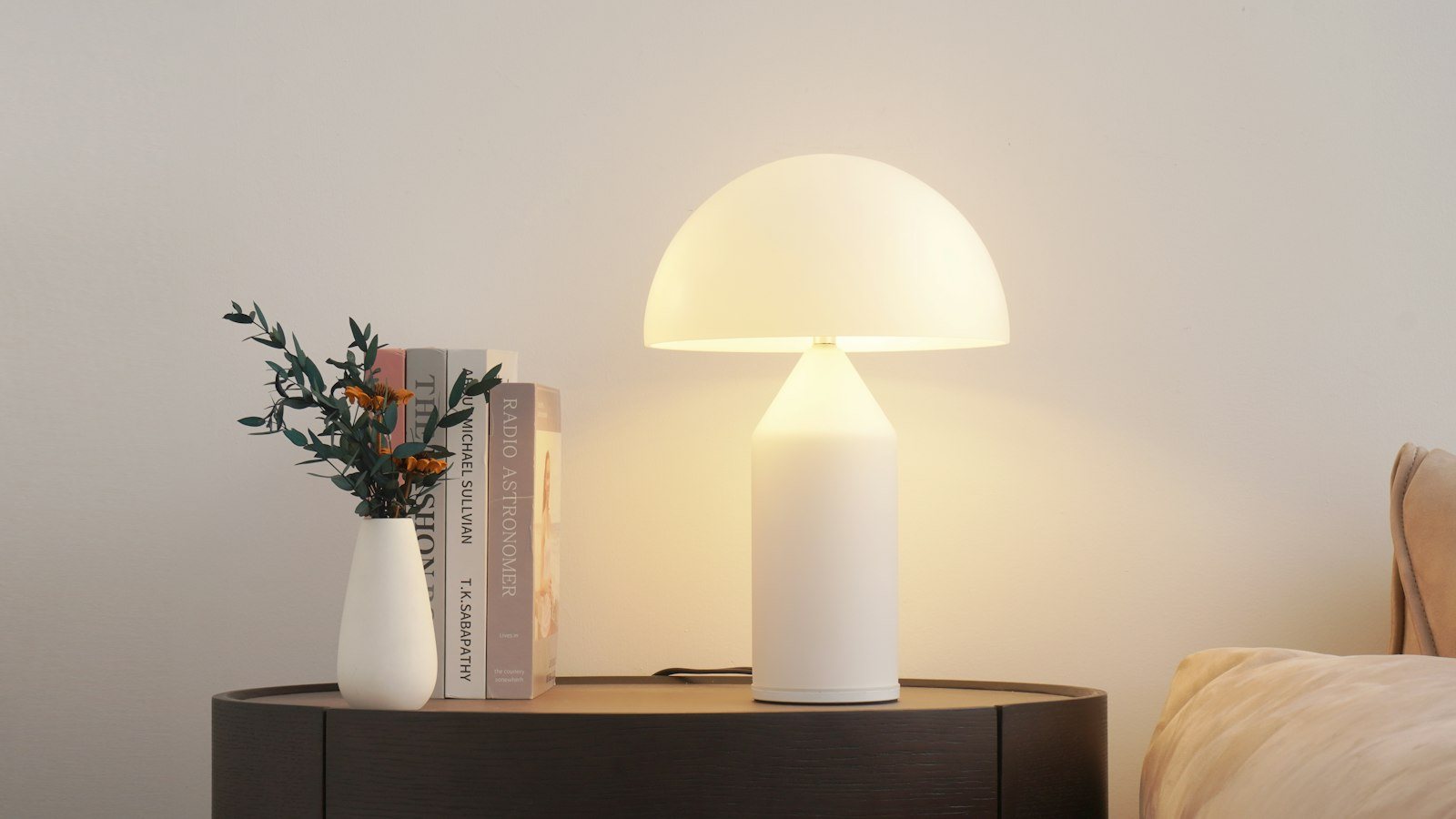 A dimmable mushroom table lamp beside books on a side table