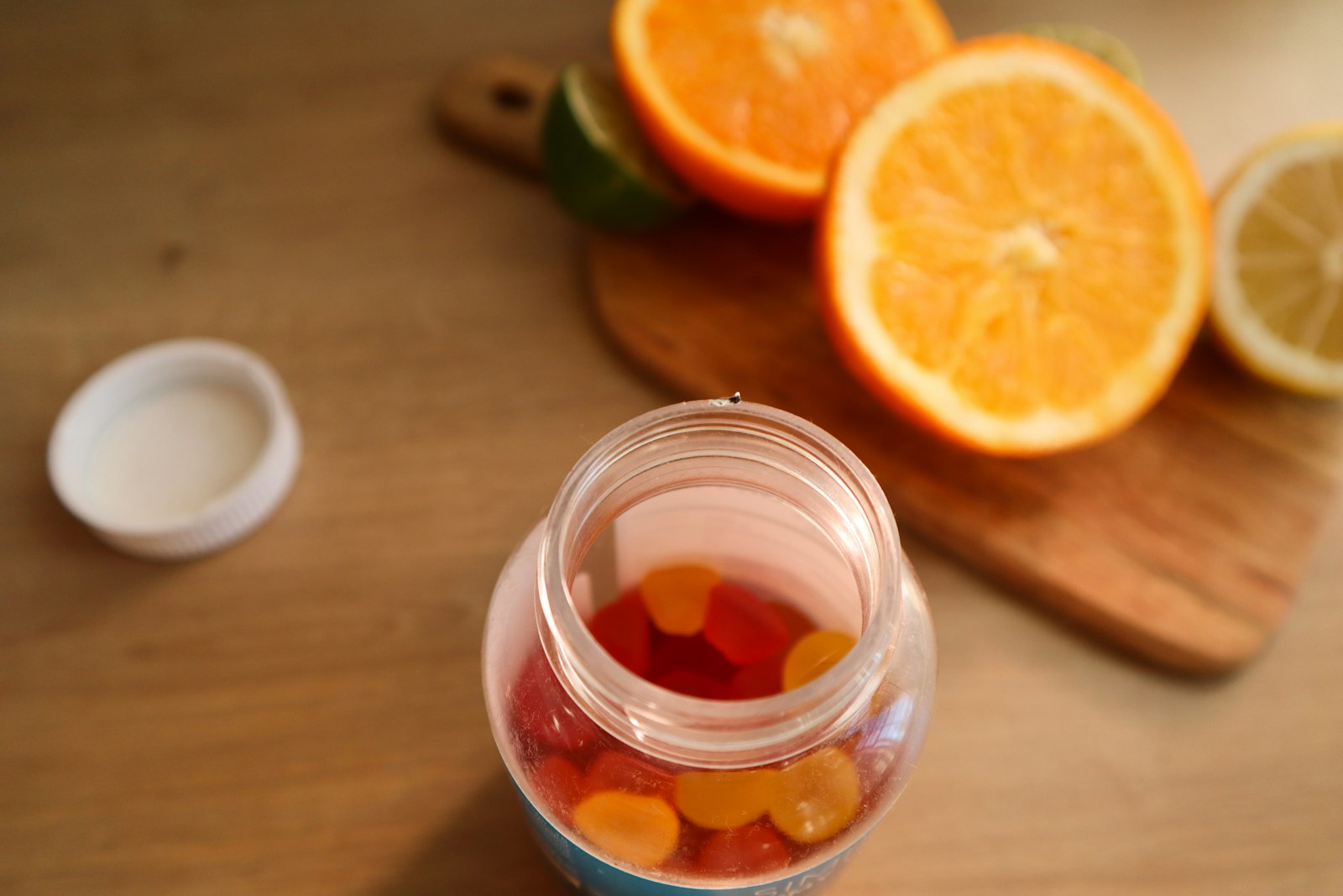 An open jar of gummy supplements next to sliced oranges - the gummy format is the worst value in the menopause supplements category