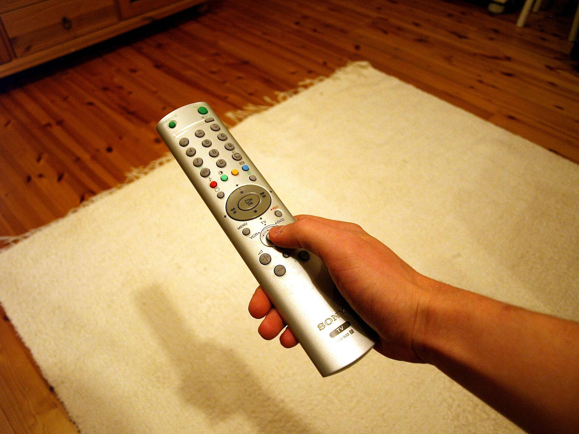 Hand pointing a TV remote at a television screen
