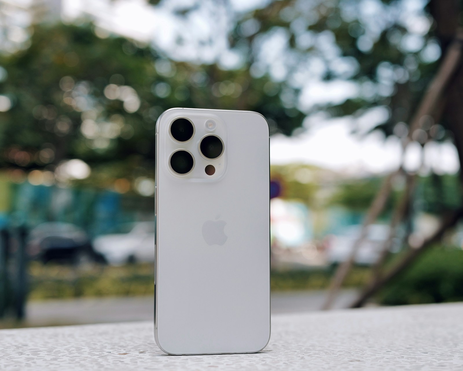 White iPhone 15 Pro standing upright on an outdoor table