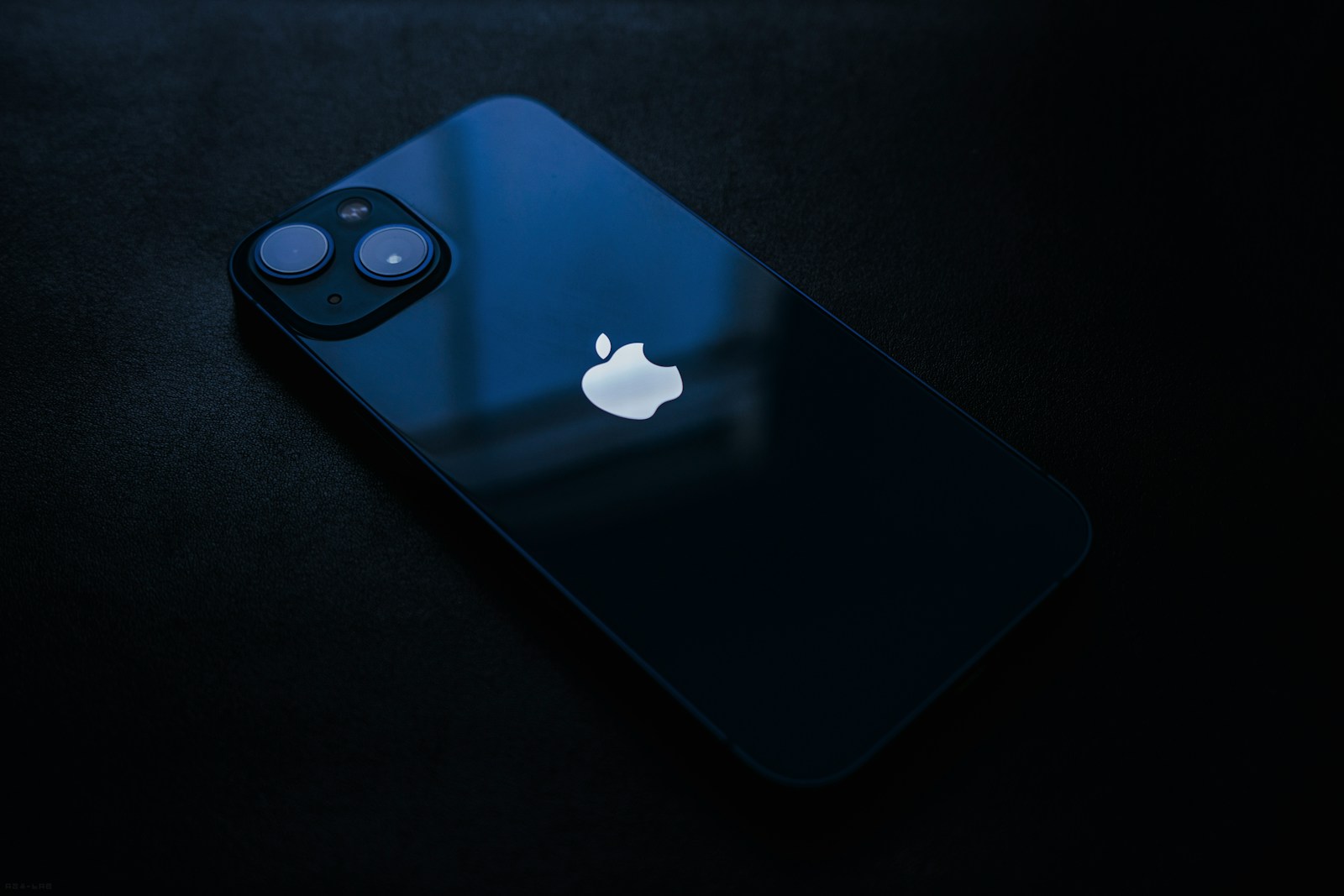 Dark blue iPhone 13 lying on a black surface