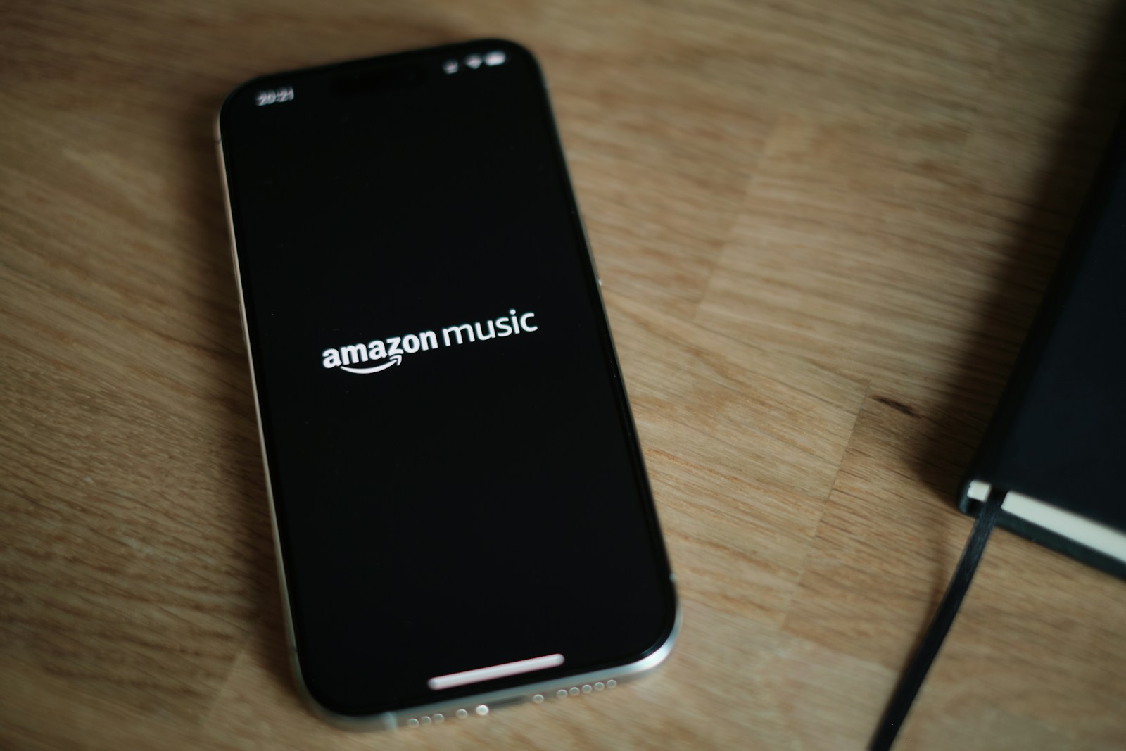 iPhone on a wooden desk next to a notebook