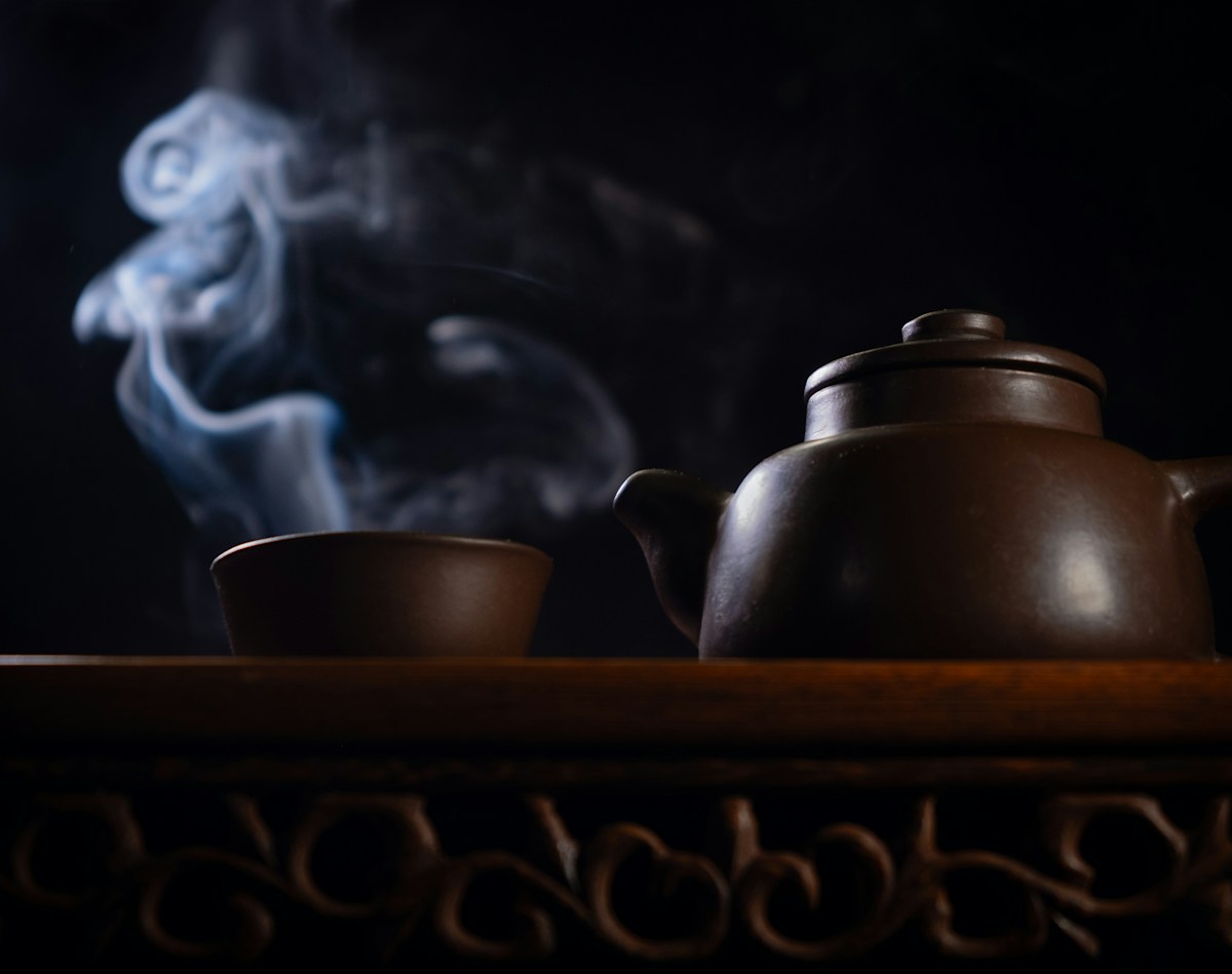 Steaming teapot and cup, as hot drinks are a common rosacea trigger in winter