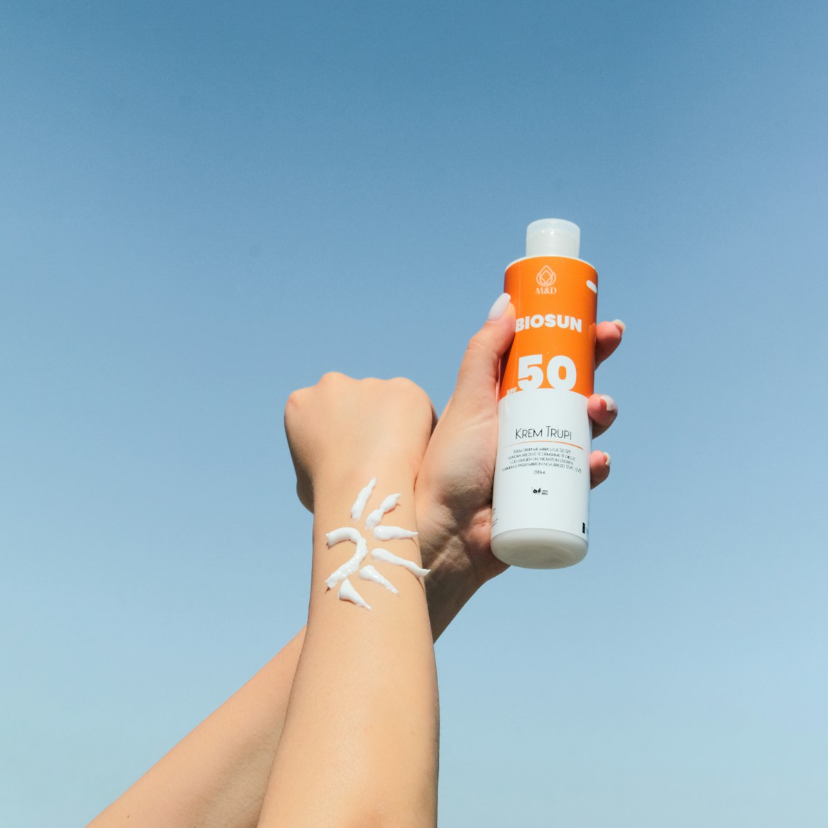 Person holding a bottle of sunscreen, the first line of defence against the most common rosacea trigger