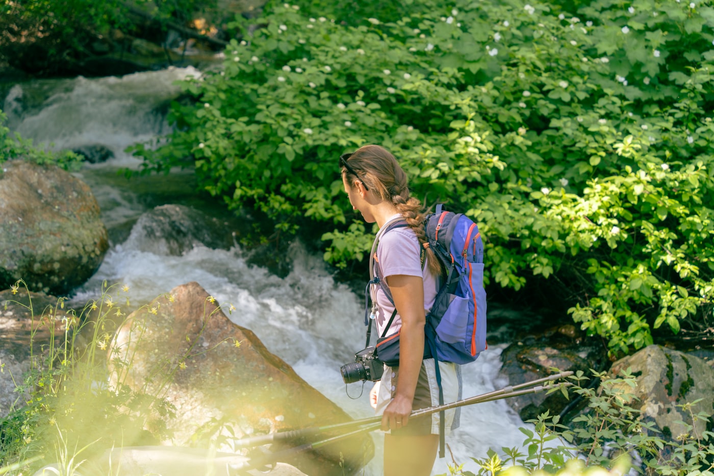 Woman with a hiking backpack beside a stream