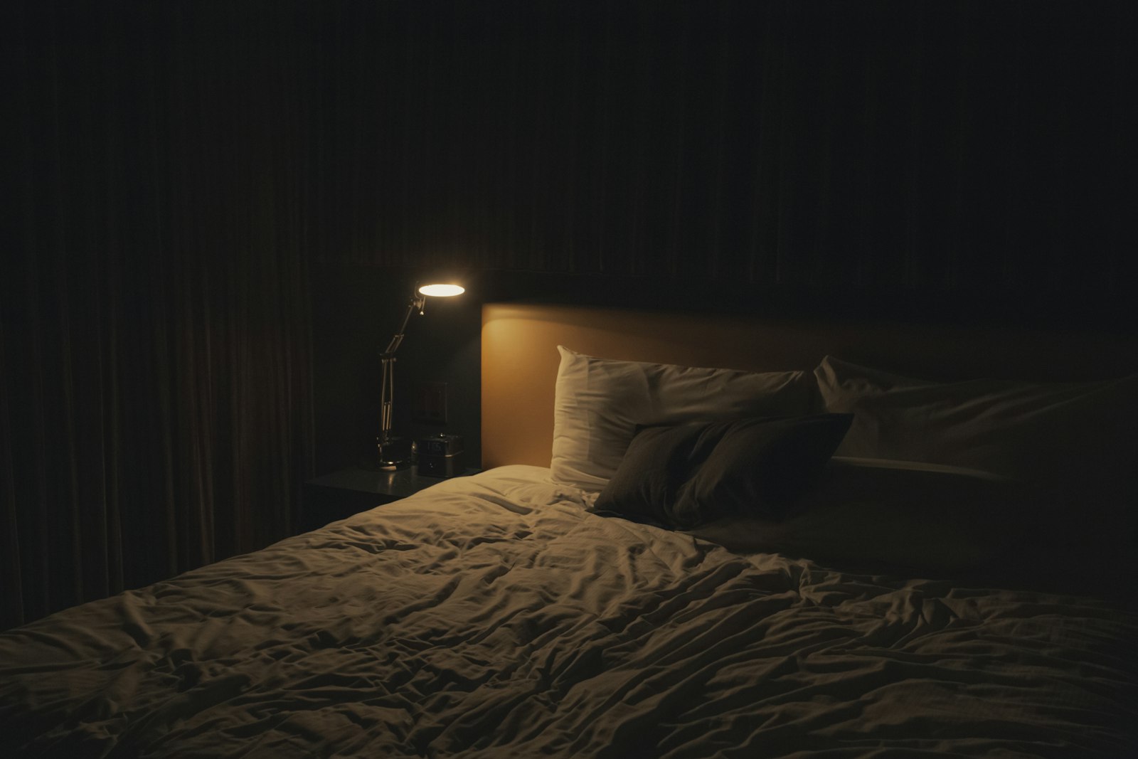 Dark bedroom at night with a phone face down on the bedside table