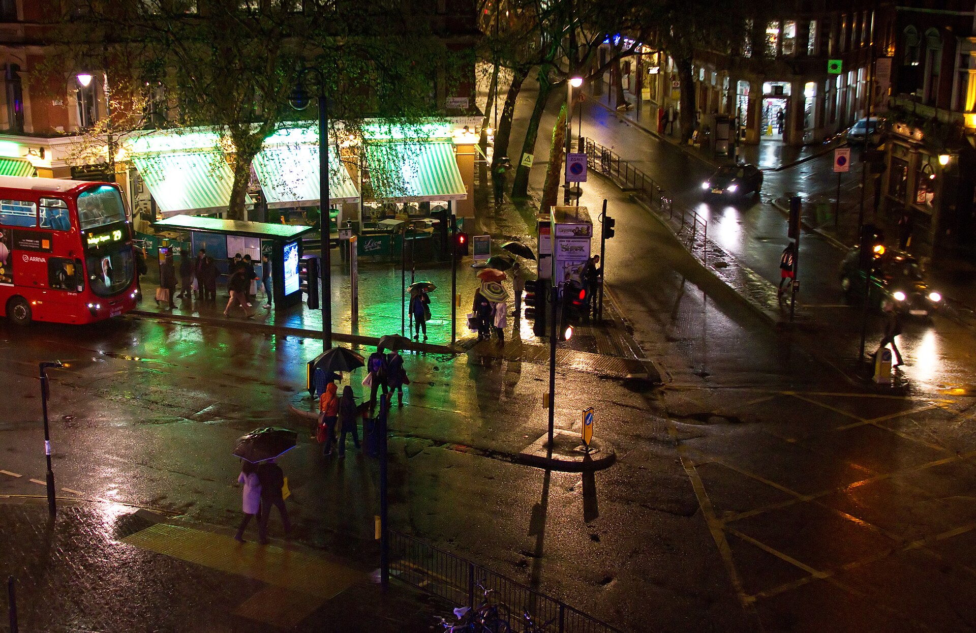A wet London street at night with a red bus and people with umbrellas, the kind of setting Slow Horses season 6 uses