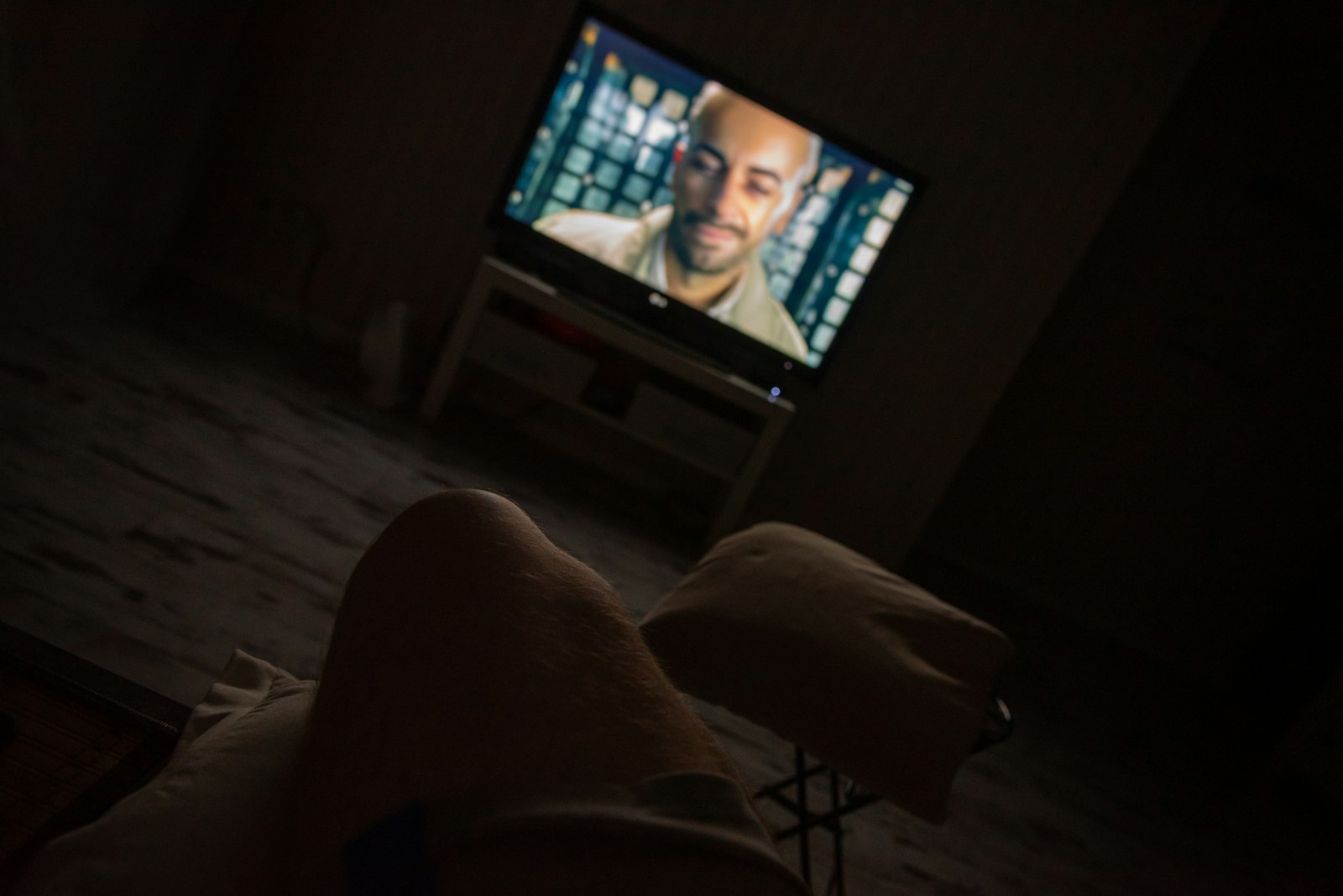 Watching television from a sofa in a dark living room at night