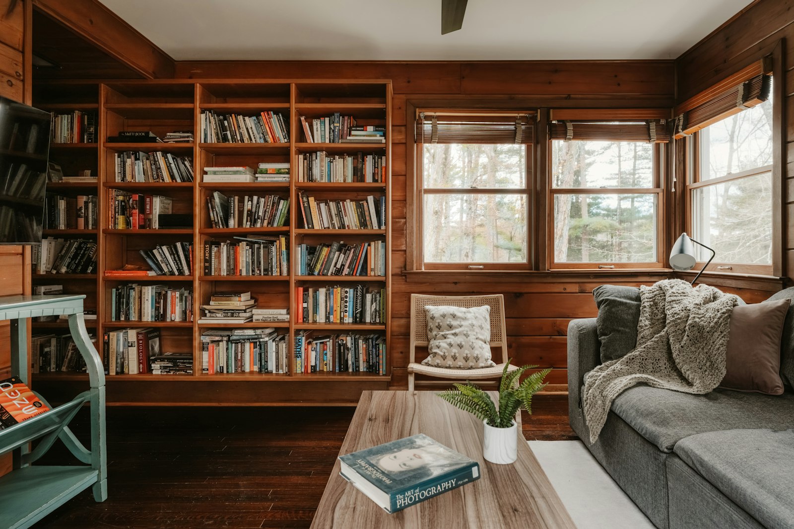 Snug room ideas 2026: a small sitting room with a wall of books and low lamp light