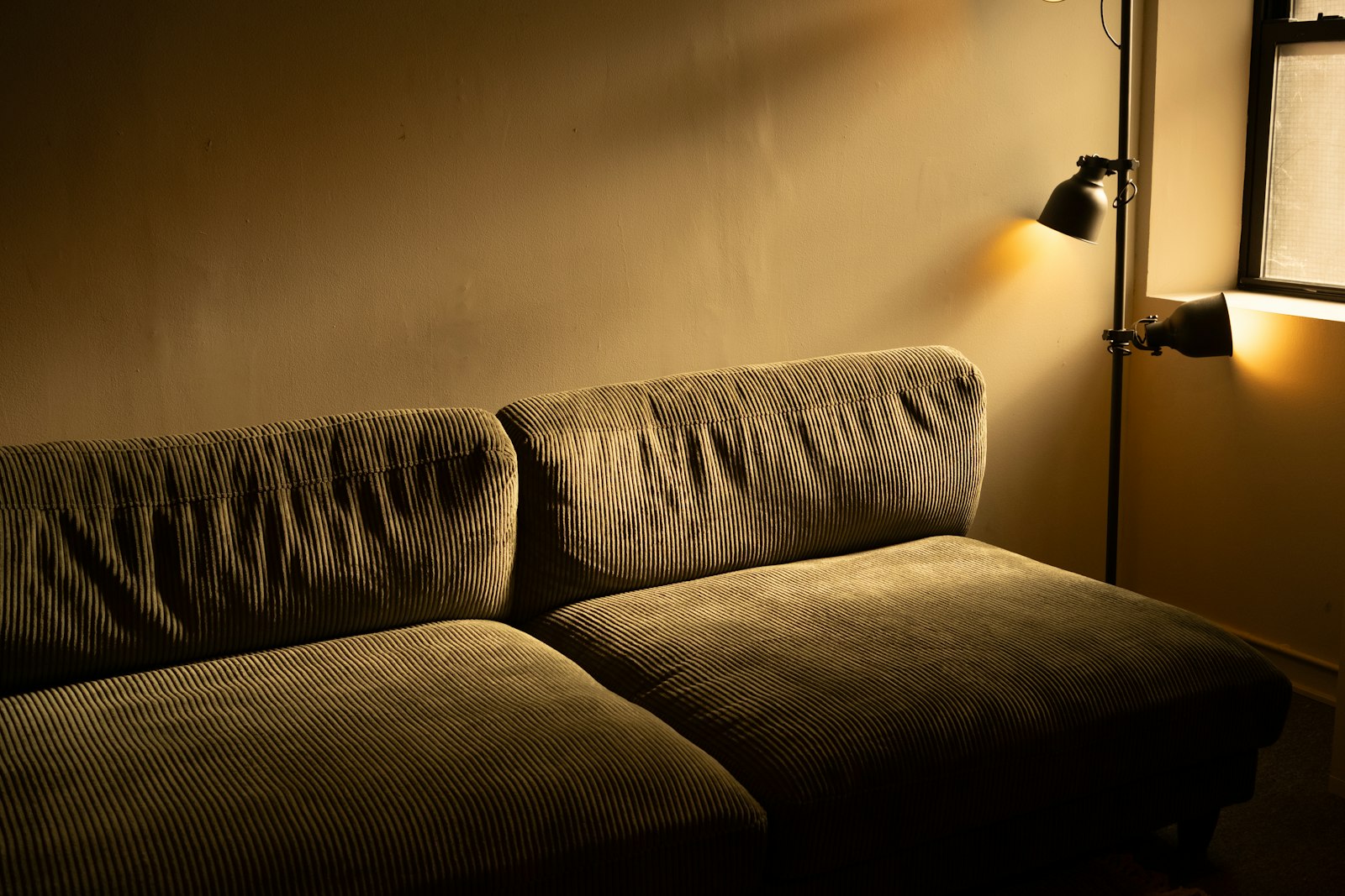 A dimly lit sofa under a single floor lamp, the lamps-only rule for a snug