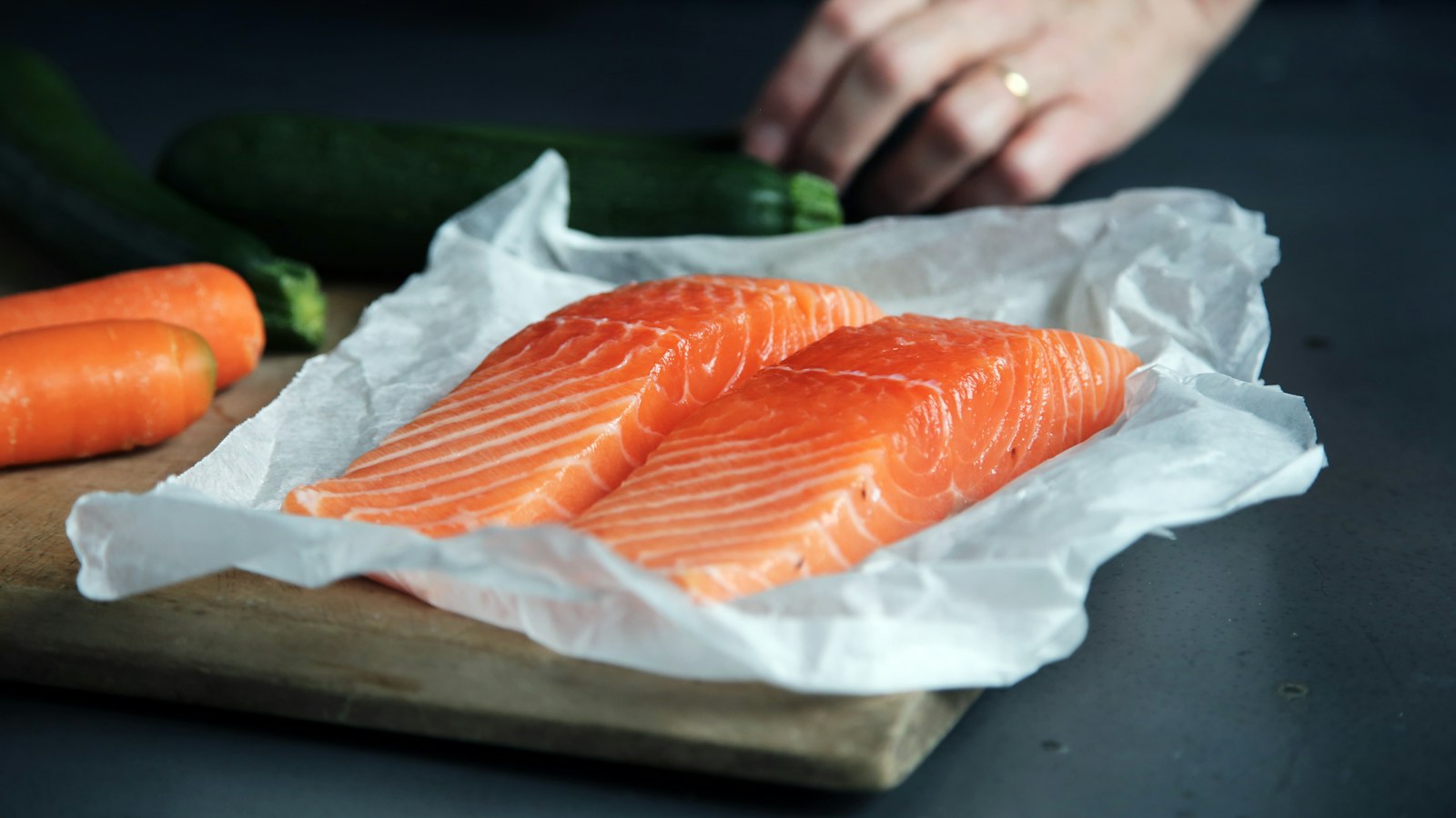 Two raw salmon fillets on paper, one of the few food sources of vitamin D relevant to a vitamin D supplement in autumn