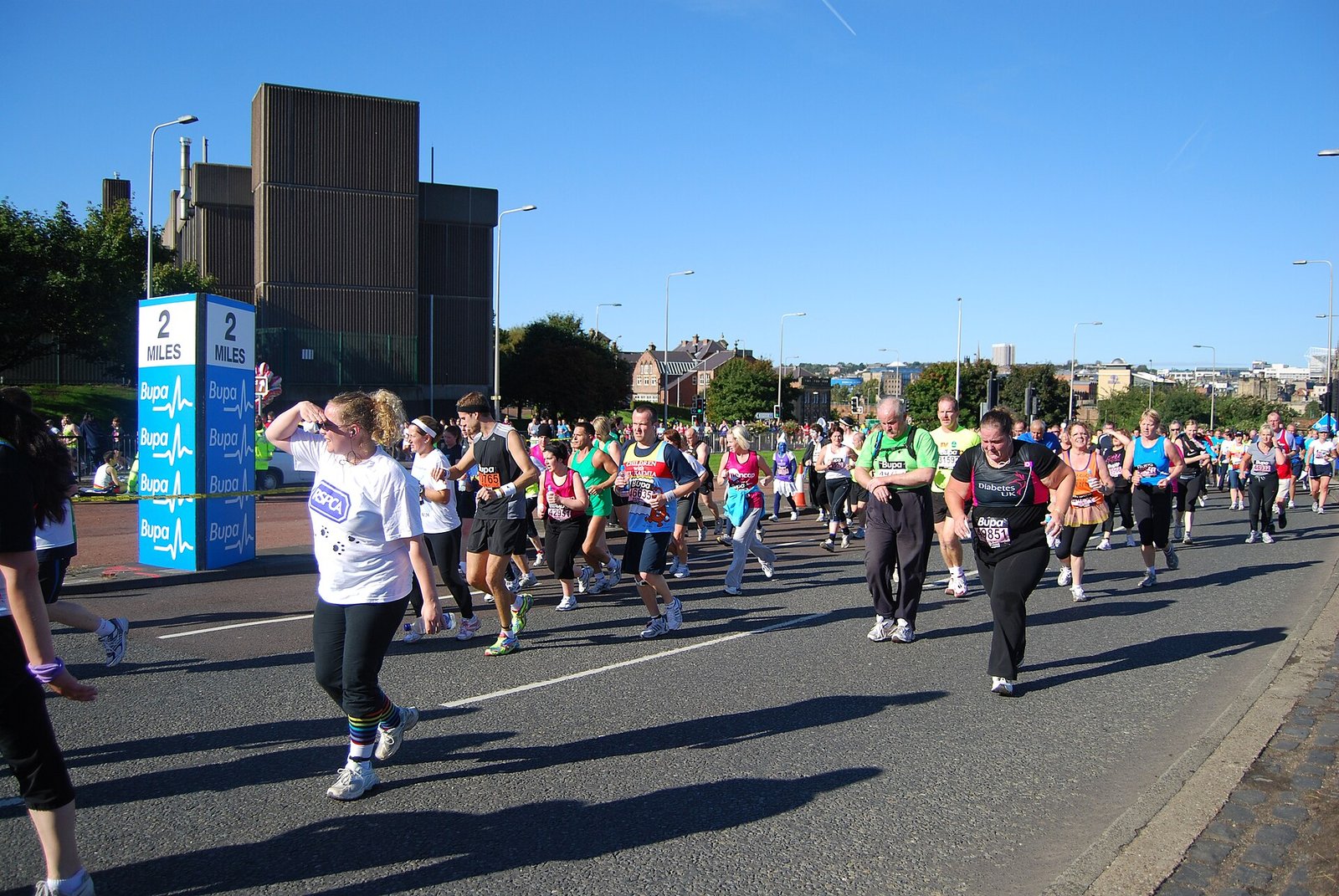A packed field of half marathon runners early in a race, most of them settling into a steady aerobic pace