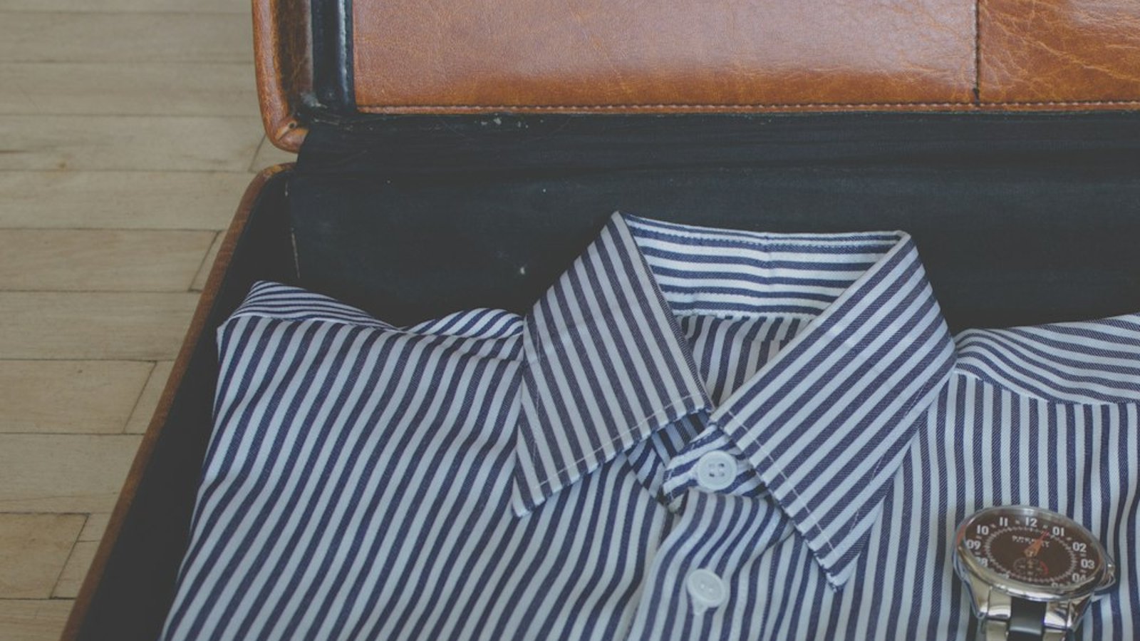 Open suitcase with neatly packed shirt and travel items, showing how to pack for the 100ml liquid rule