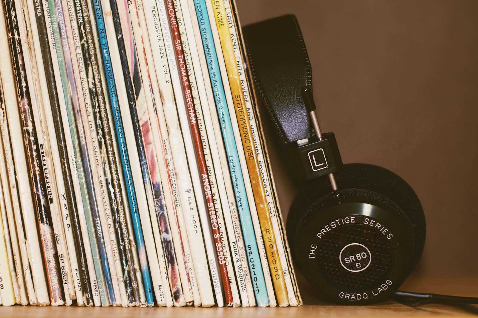Black headphones resting against a row of vintage vinyl albums, a snapshot of the best British albums of 2026 on record