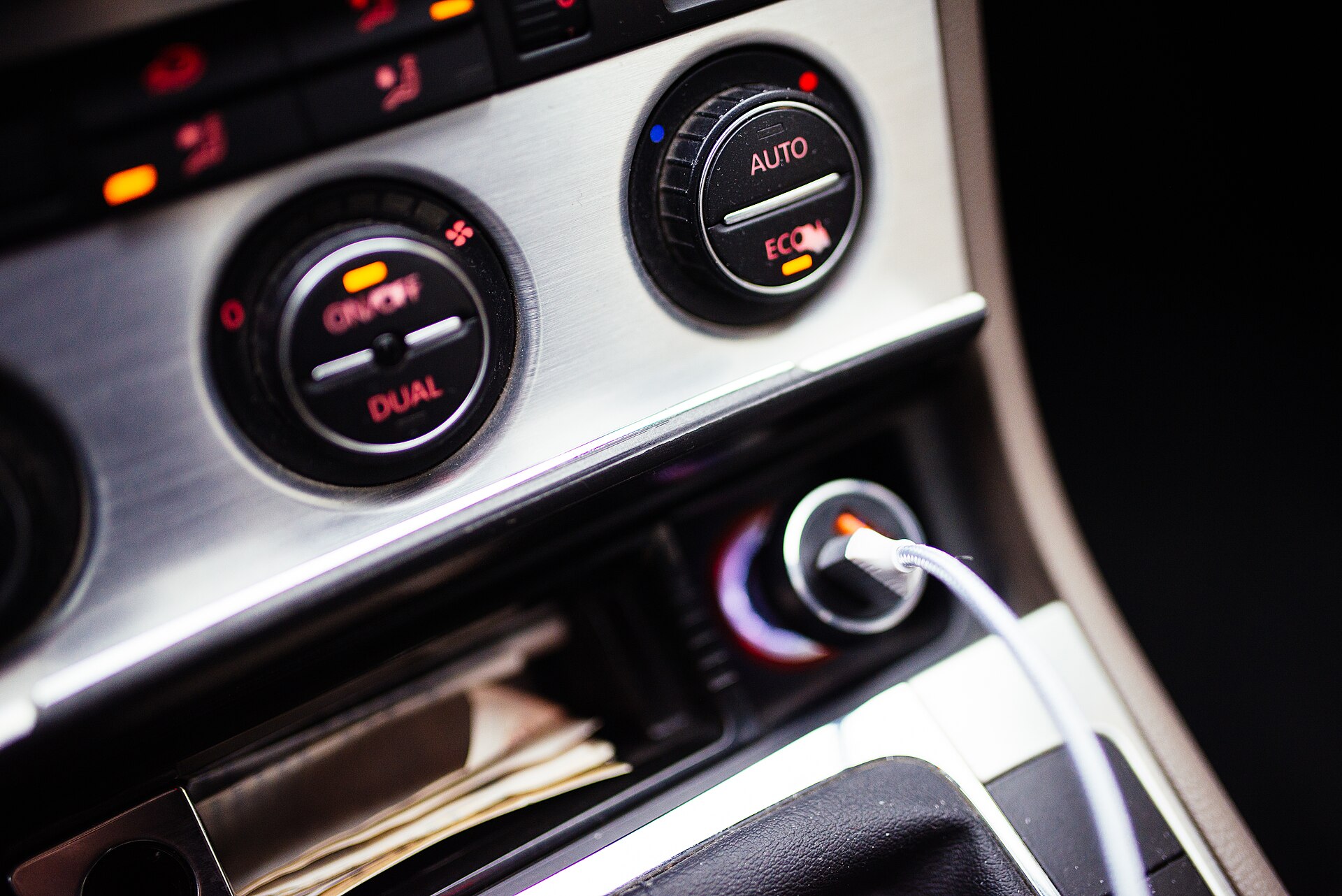 Car dashboard at night with a charging cable plugged in, the sort of drain that can flatten a battery before winter