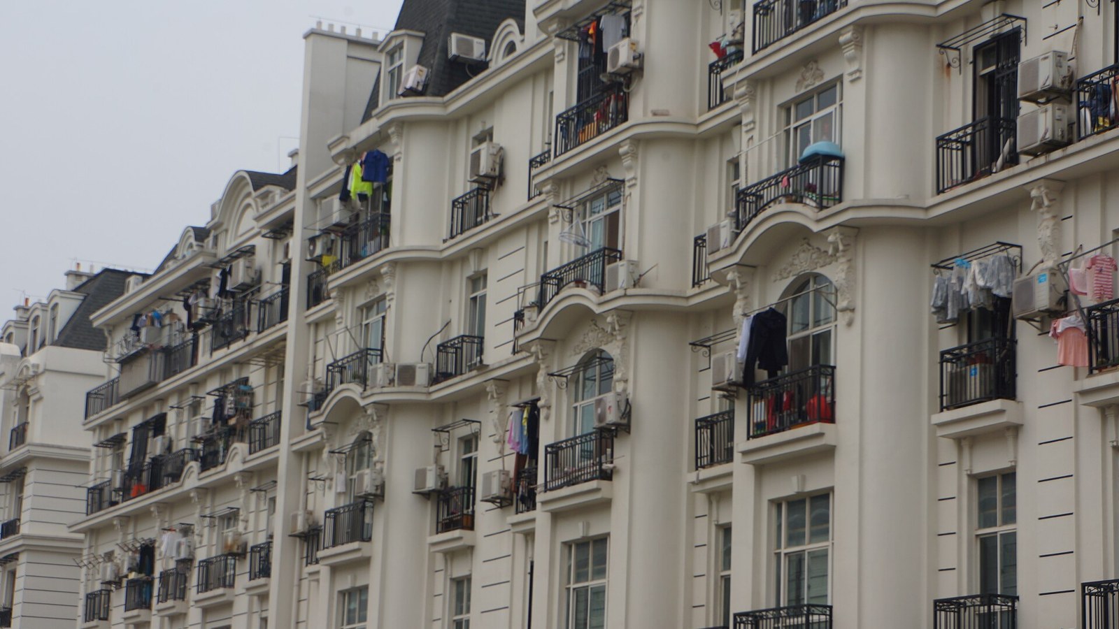 Washing hung from balconies on a white apartment block, showing how flats dry laundry without a garden