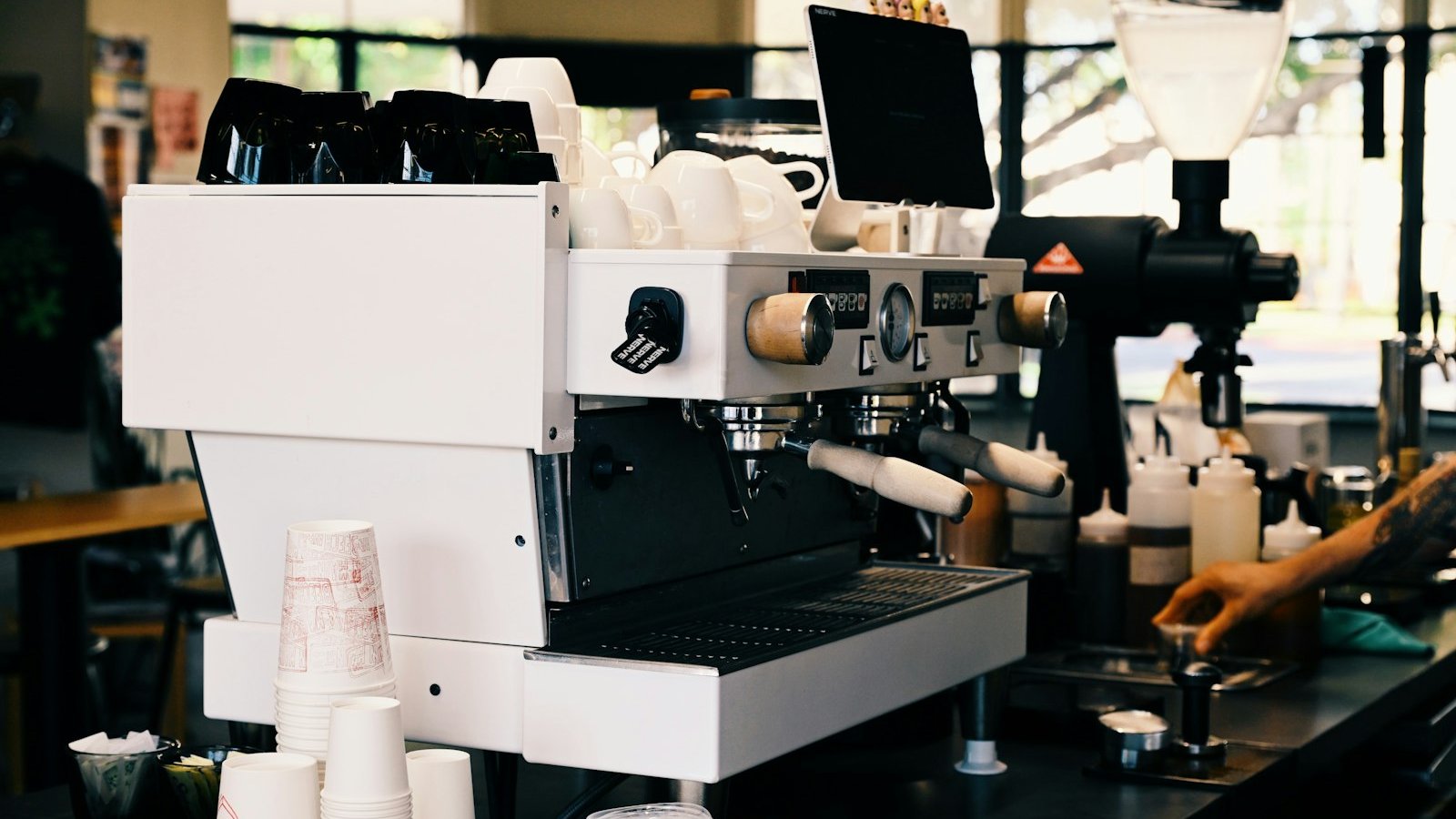 Barista working an espresso machine in a busy cafe, where caffeine cut-off time is decided by what goes in the cup