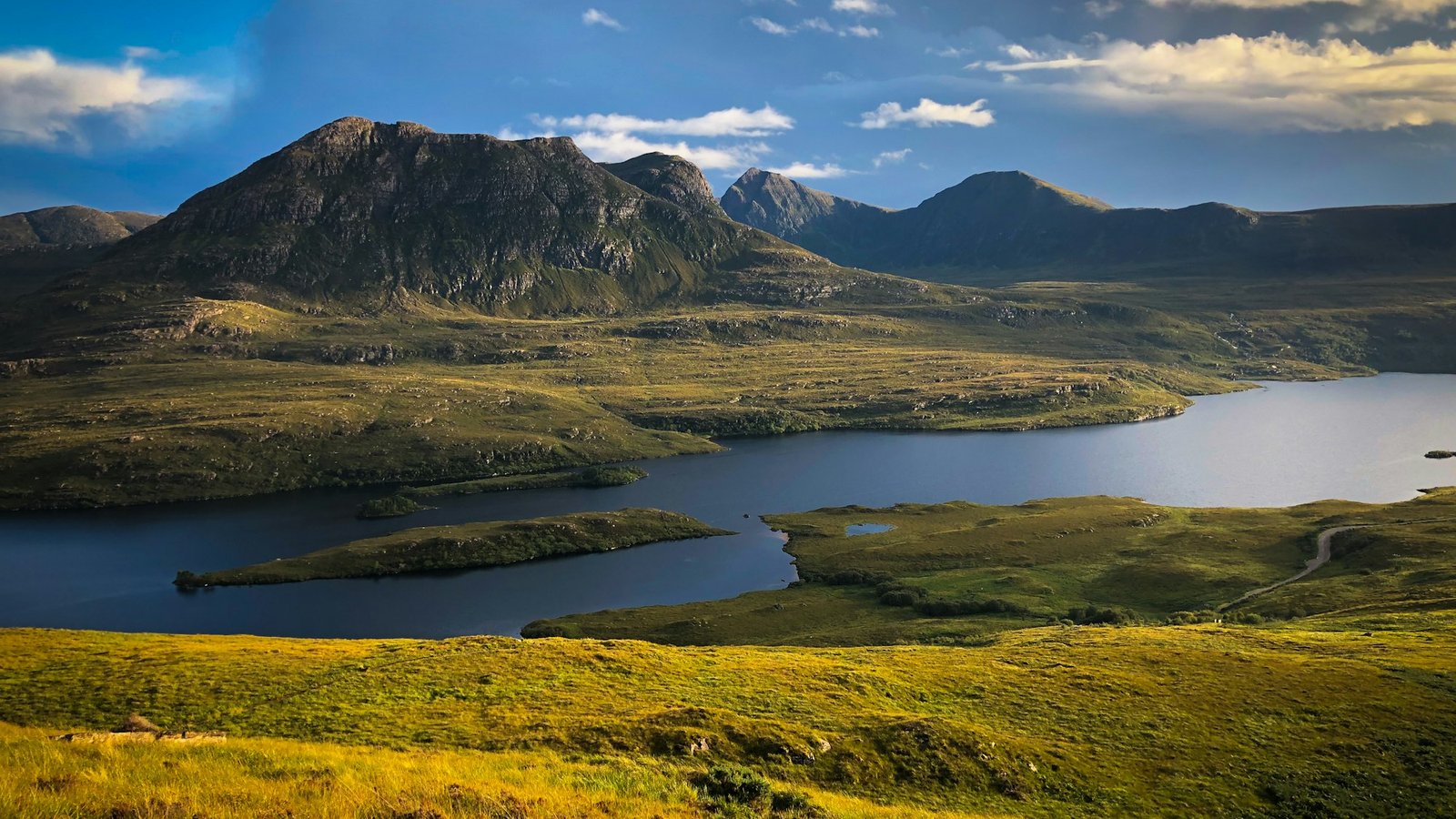 Green Highland hills beside a loch, the Scottish backdrop to Celebrity Traitors series 2