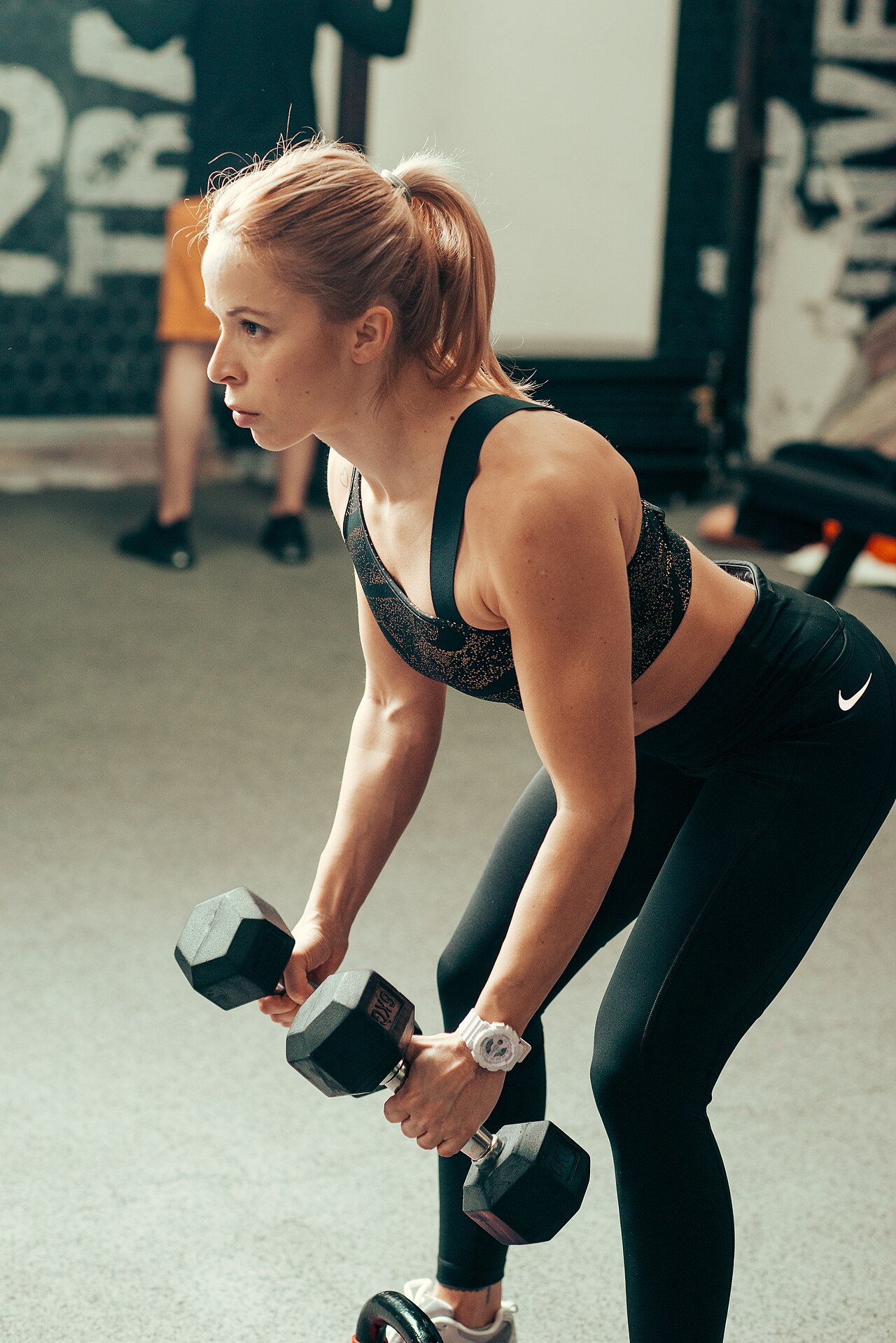 Woman lifting dumbbells in a gym, the setting where creatine for women has its best evidence