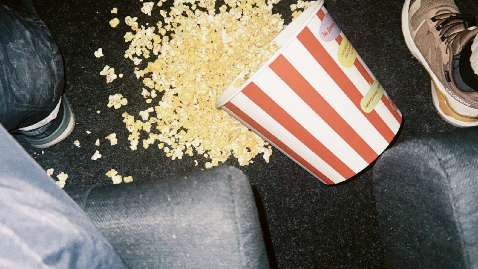 Spilled popcorn bucket on a dark cinema floor at a late-night Halloween screening