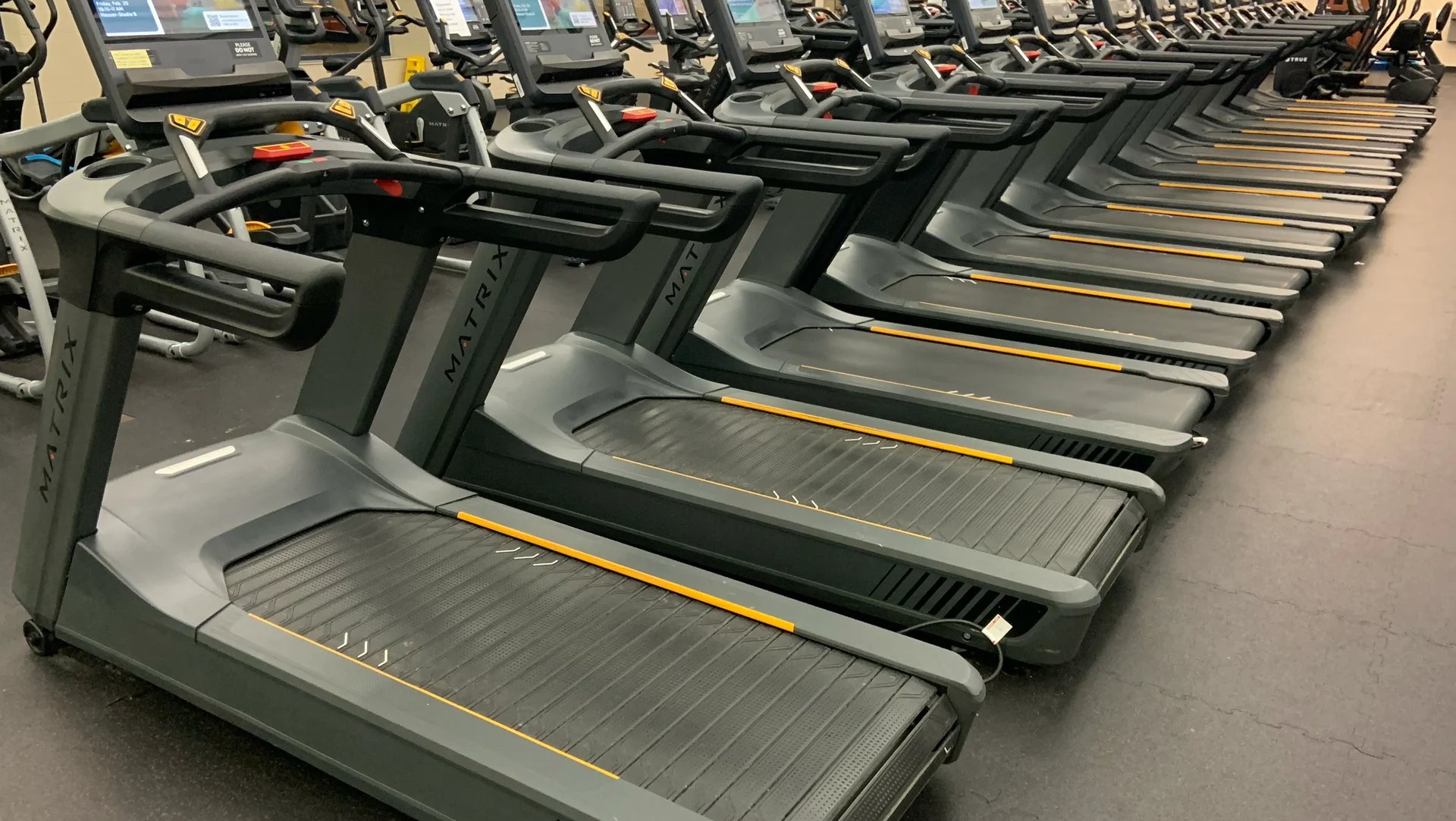 Row of treadmills in a gym, the kind of running volume behind many hyrox injuries