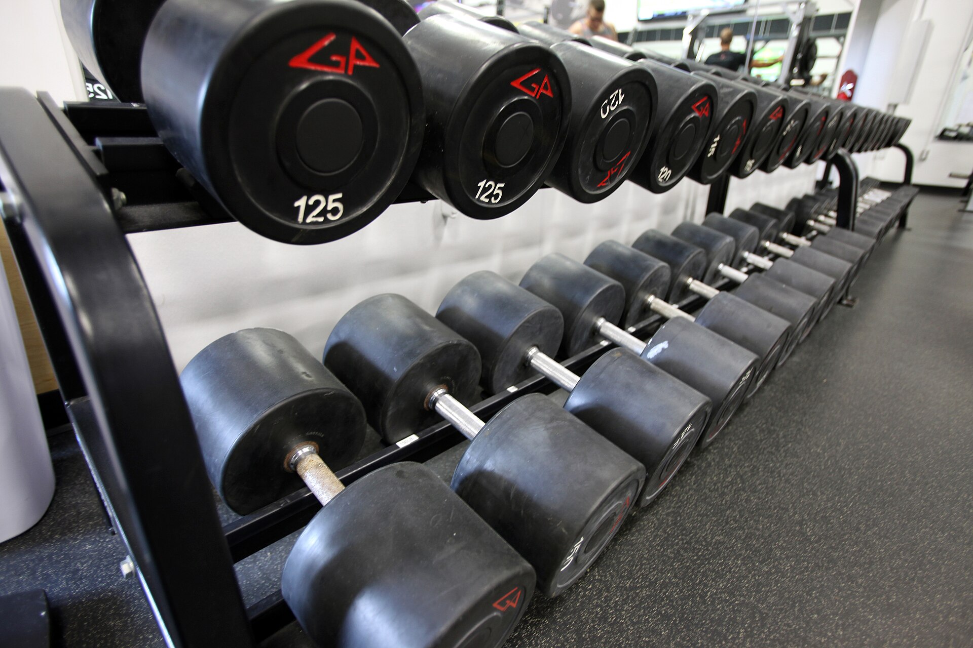 Dumbbells lined up on a rack in a gym, strength work to prepare for hyrox and reduce hyrox injuries