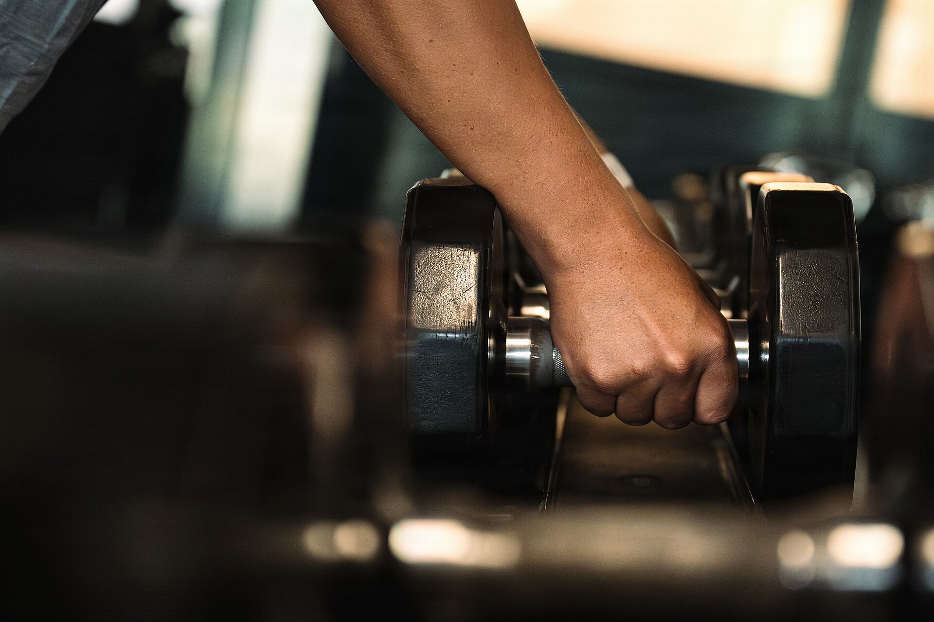 Person picking up dumbbells in a gym during strength training for hyrox