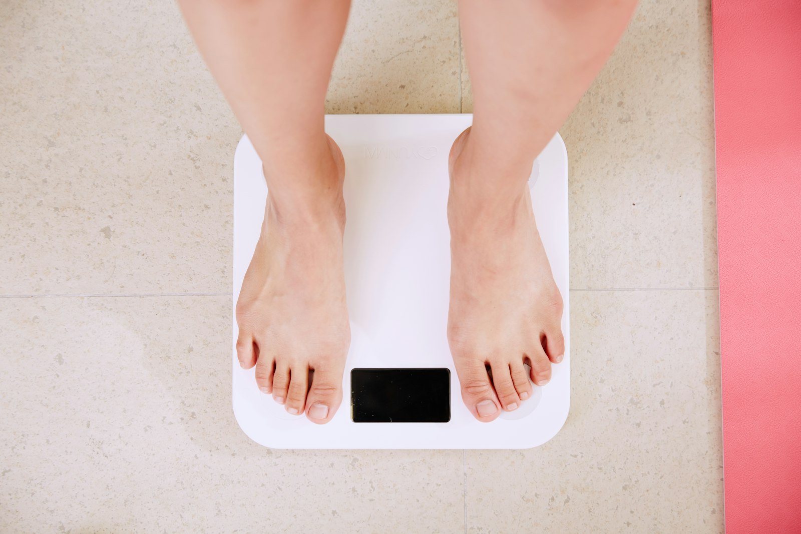 Person standing on a white digital bathroom scale, checking the result of intermittent fasting for weight loss