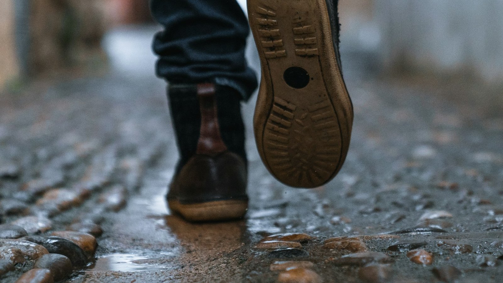 Boots stepping over wet cobbles, the kind of damp pavement a Japanese walking workout has to cope with in October