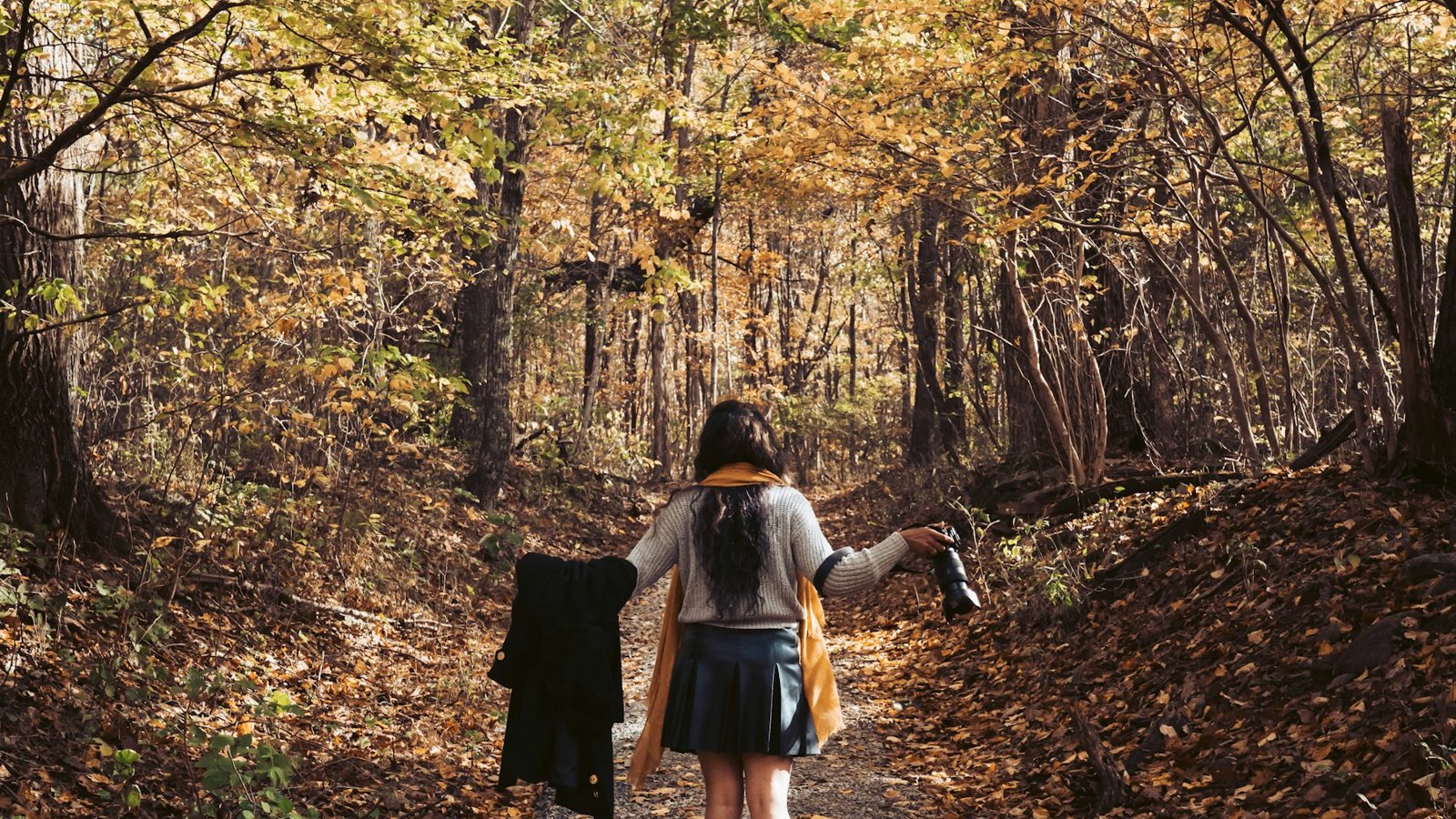Woman walking through golden autumn woodland, a Japanese walking workout in the seasonal light before the clocks change