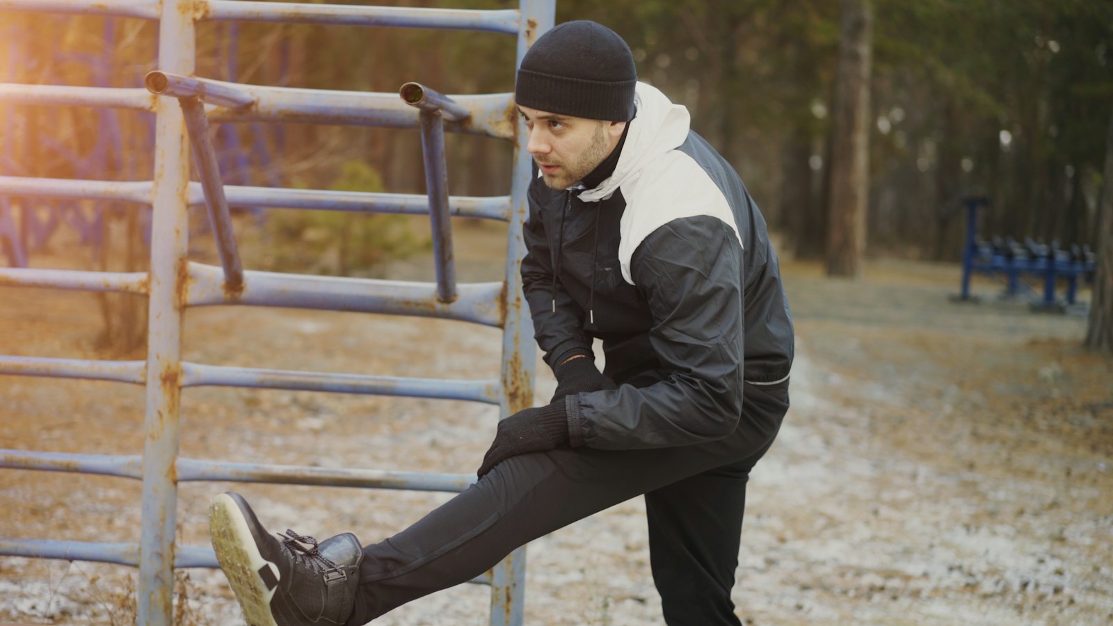 A man stretching his legs outdoors, a free alternative when asking whether massage guns work for recovery