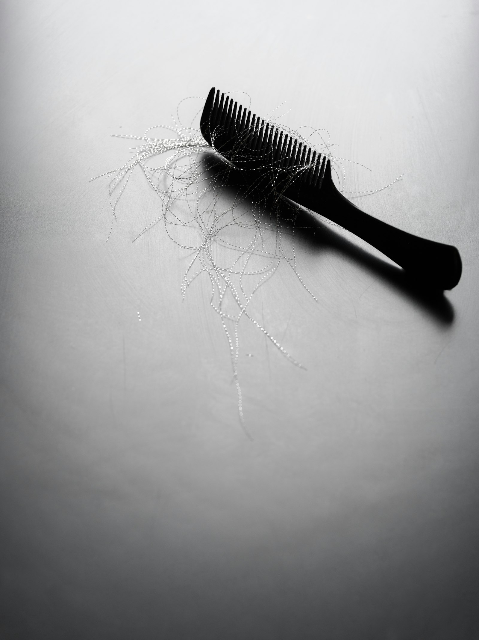 Black comb holding loose strands of hair, a common worry for people searching for rosemary oil for hair growth