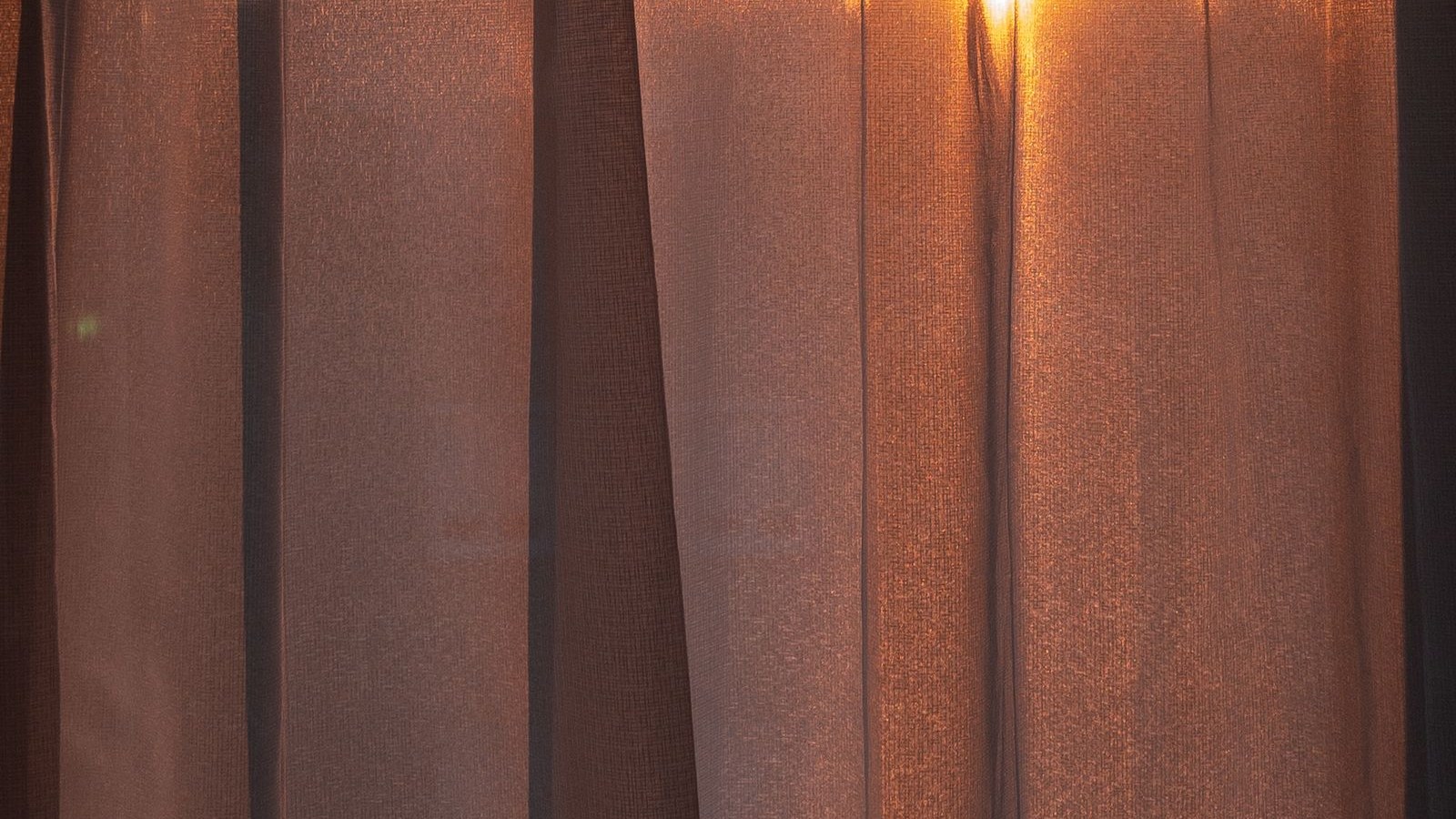 Thin curtains glowing orange as the first light comes through, the look a sunrise alarm clock is built to copy